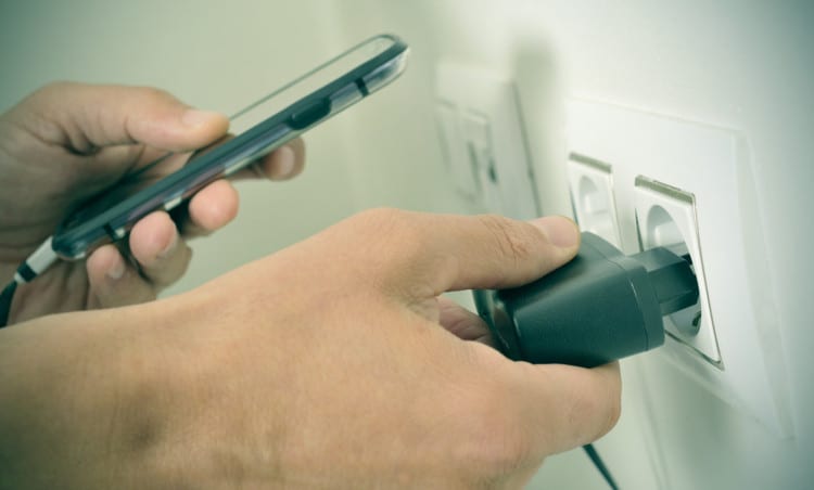 stock-photo-closeup-of-the-hands-of-a-man-plugging-in-the-plug-of-his-smpartphone-in-a-socket-with-a-filter-260244584
