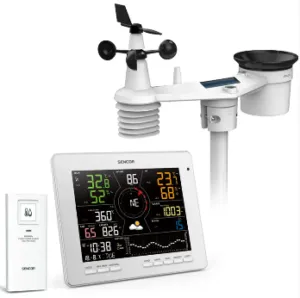 The image displays a weather station with a digital display, wind speed gauge, and a wind vane, along with a solar panel and battery charging unit.Obsah generovaný pomocí AI může být nesprávný.